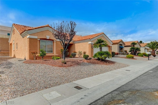 view of front facade with a tiled roof, stucco siding, an attached garage, and driveway