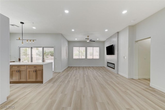 unfurnished living room featuring light wood finished floors, baseboards, recessed lighting, a fireplace, and a ceiling fan