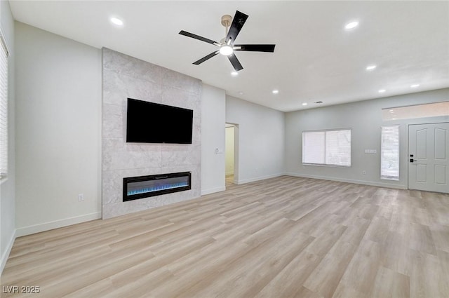 unfurnished living room with a ceiling fan, baseboards, recessed lighting, a tile fireplace, and light wood-type flooring