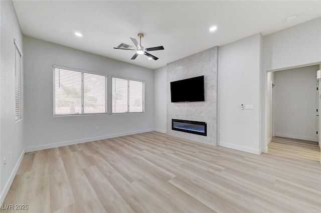 unfurnished living room featuring baseboards, a fireplace, light wood-style flooring, and a ceiling fan