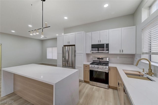 kitchen featuring a sink, light wood-type flooring, appliances with stainless steel finishes, and decorative backsplash