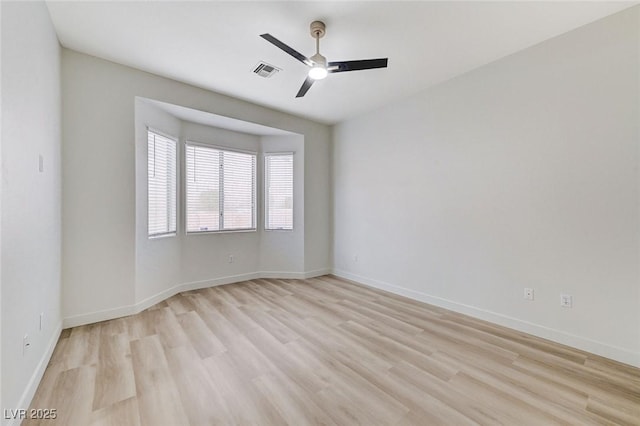 spare room with visible vents, light wood-style flooring, baseboards, and a ceiling fan