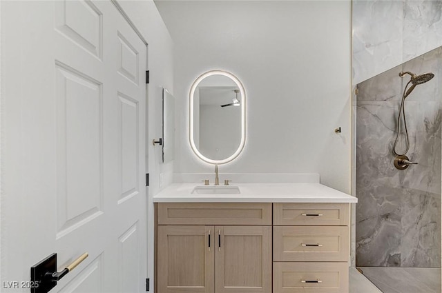 bathroom with a tile shower and vanity