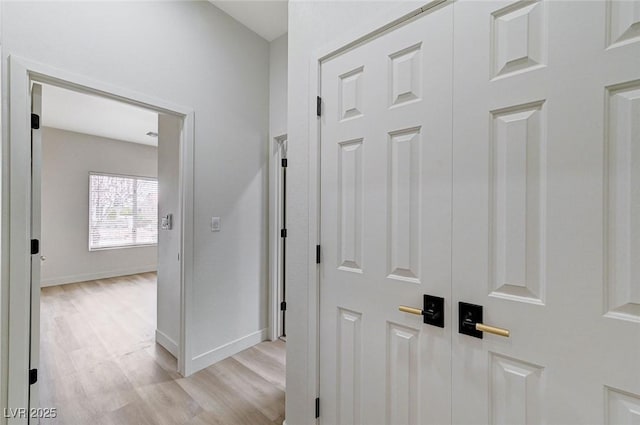 corridor featuring baseboards and light wood finished floors