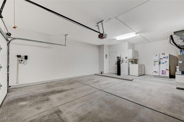 garage featuring washing machine and dryer, white refrigerator with ice dispenser, and a garage door opener