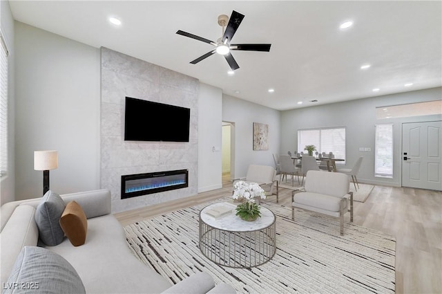 living room featuring baseboards, ceiling fan, recessed lighting, a fireplace, and wood finished floors