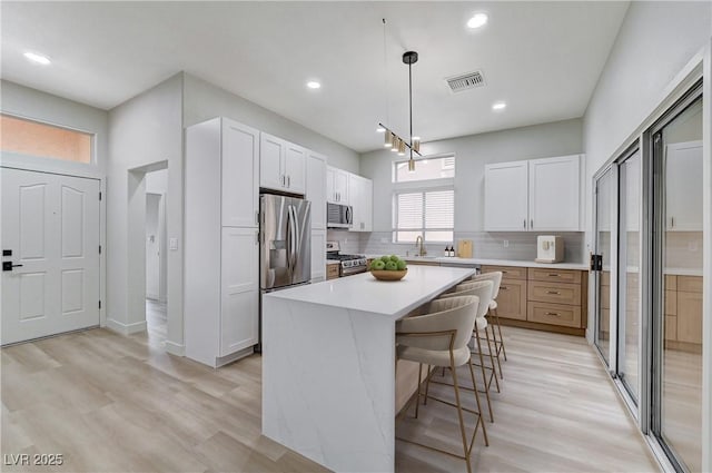 kitchen with visible vents, light countertops, white cabinets, stainless steel appliances, and a sink