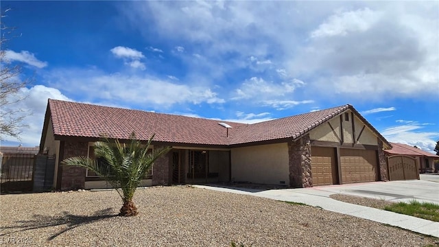 view of front of house with concrete driveway, a tiled roof, a garage, and stucco siding