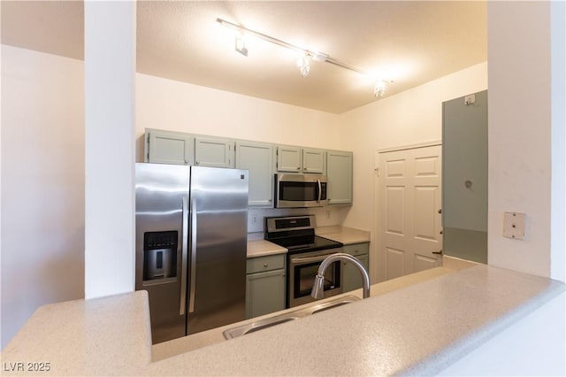 kitchen with light countertops, rail lighting, a peninsula, and stainless steel appliances