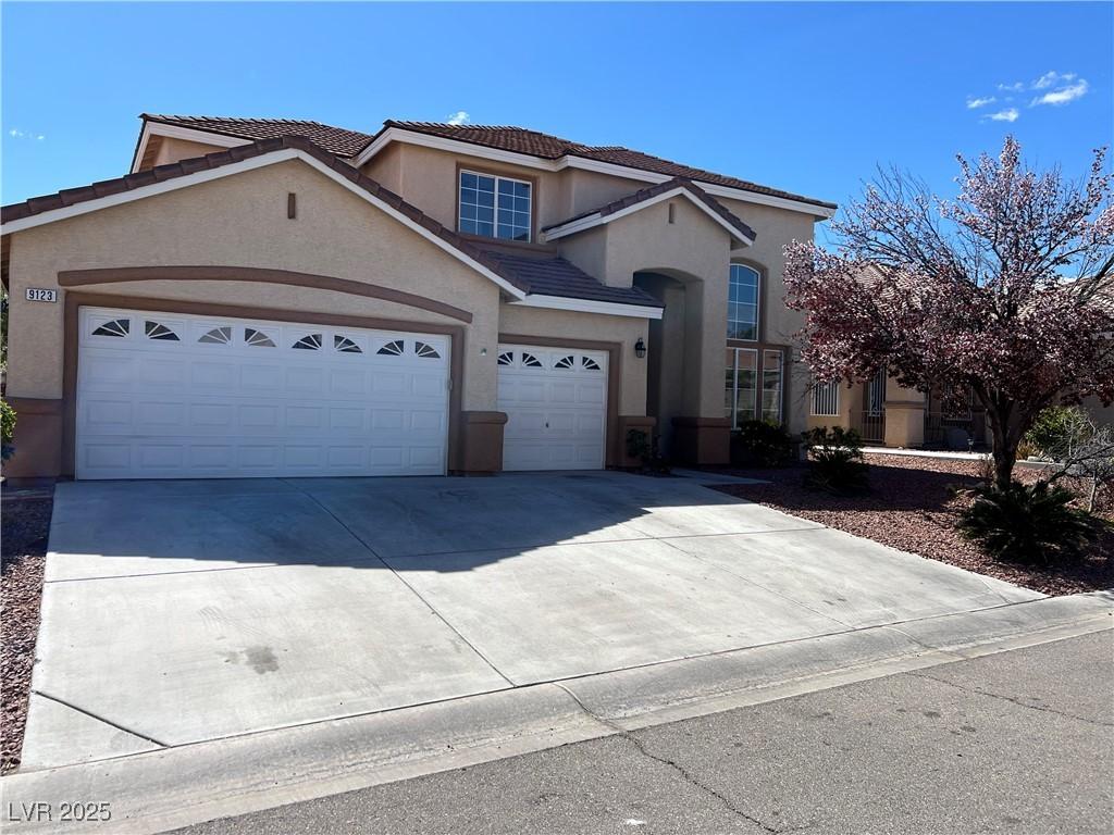 view of front of home with stucco siding, a garage, concrete driveway, and a tiled roof