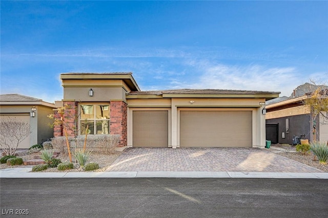 prairie-style house featuring decorative driveway, an attached garage, and stucco siding