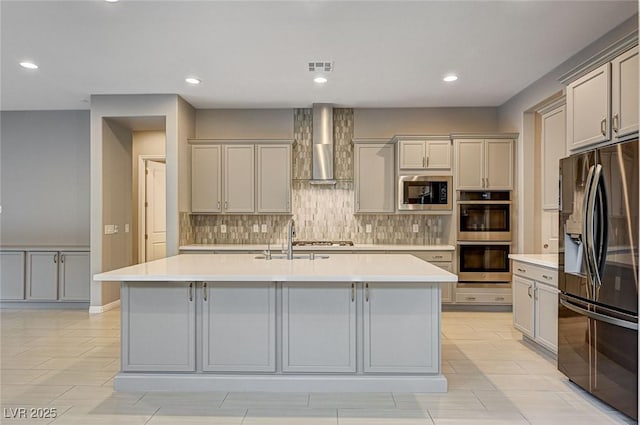 kitchen with backsplash, appliances with stainless steel finishes, wall chimney exhaust hood, and light countertops