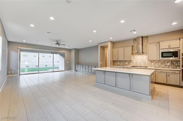 kitchen featuring built in microwave, a sink, light countertops, wall chimney exhaust hood, and tasteful backsplash