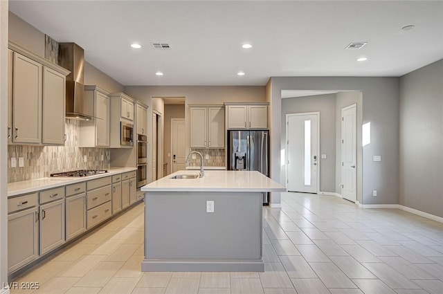 kitchen with gray cabinetry, a sink, stainless steel appliances, wall chimney exhaust hood, and light countertops