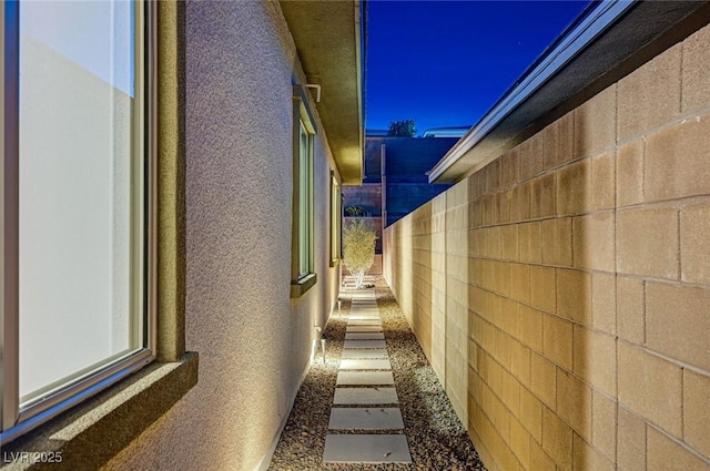 view of side of home featuring fence and stucco siding