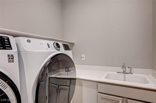 laundry room featuring washing machine and clothes dryer, cabinet space, and a sink