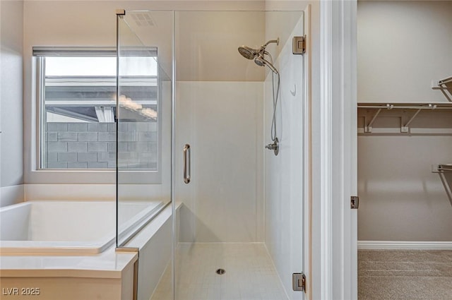 bathroom featuring a walk in closet, a shower stall, and a bath