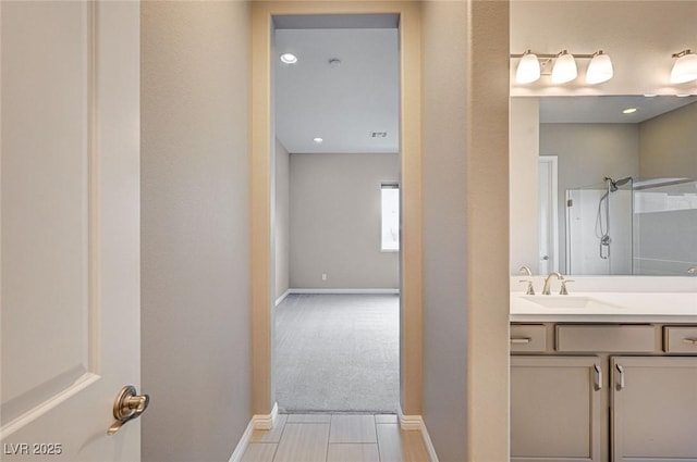 bathroom featuring a shower, baseboards, and vanity