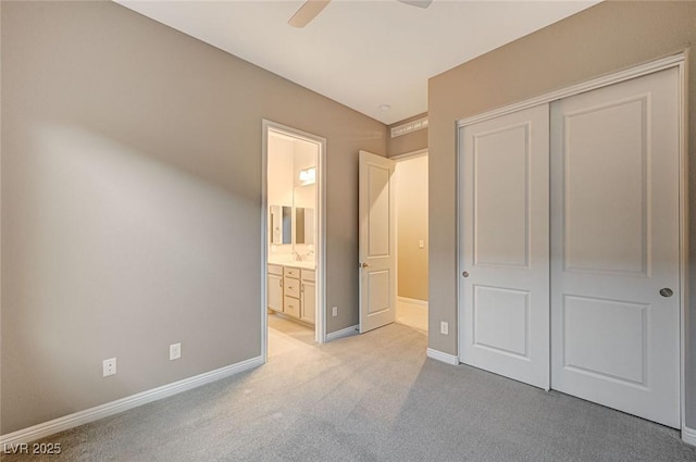 unfurnished bedroom with connected bathroom, baseboards, light carpet, a closet, and a ceiling fan