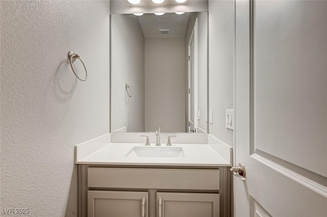 bathroom with vanity, a textured wall, and visible vents