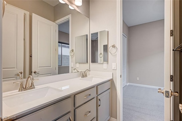 bathroom with double vanity, baseboards, and a sink