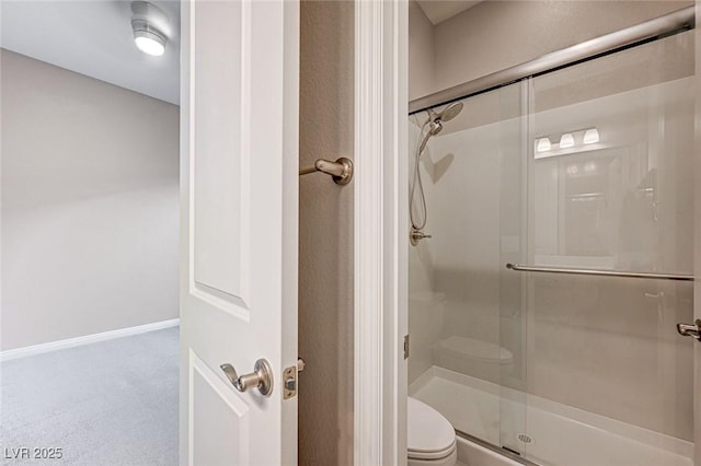 full bathroom with a shower stall, toilet, and baseboards