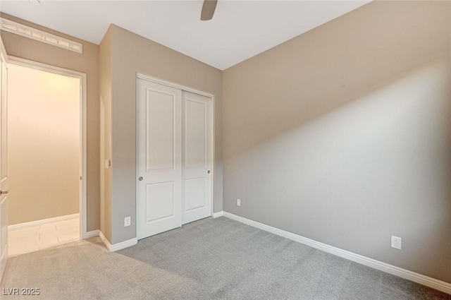 unfurnished bedroom with a closet, baseboards, carpet, and a ceiling fan