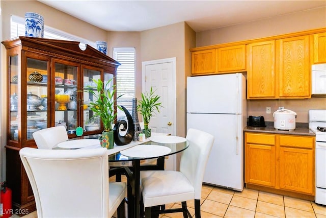 kitchen with light tile patterned floors, brown cabinets, and white appliances