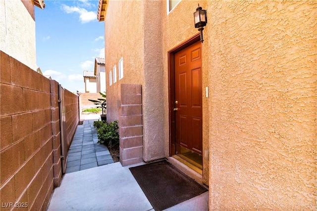 entrance to property with stucco siding and fence