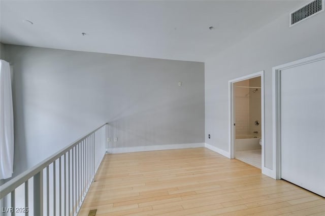 hall with wood finished floors, visible vents, and baseboards