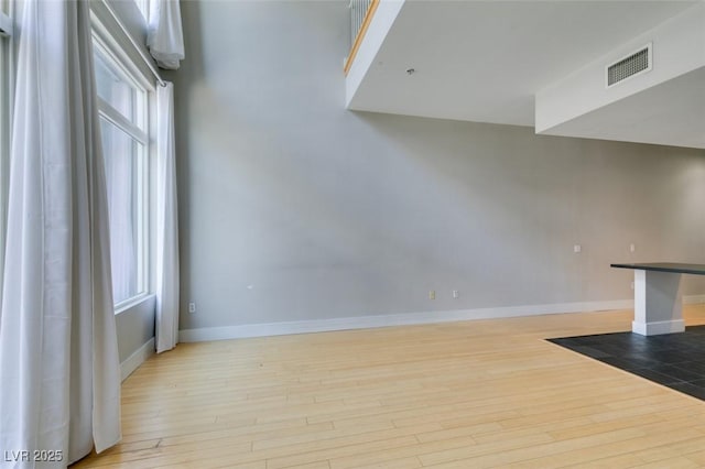 unfurnished living room with visible vents, baseboards, and wood finished floors