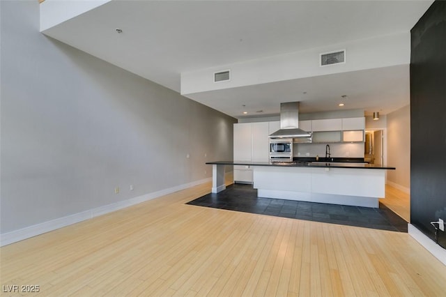 kitchen featuring ventilation hood, visible vents, dark countertops, and white cabinetry