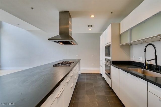 kitchen with visible vents, stainless steel appliances, a sink, dark countertops, and wall chimney range hood