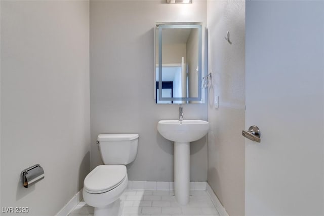 half bath with baseboards and toilet