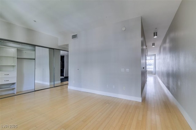 interior space with a closet, baseboards, visible vents, and light wood finished floors