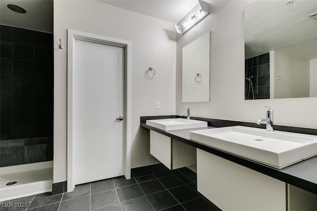 full bathroom featuring tile patterned flooring, tiled shower, and a sink