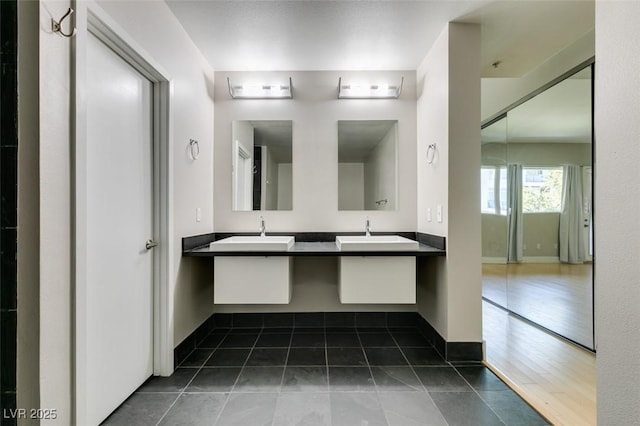 bathroom with a sink, baseboards, double vanity, and tile patterned flooring