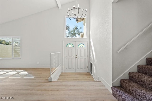 entrance foyer with beam ceiling, high vaulted ceiling, light wood-style flooring, an inviting chandelier, and stairs