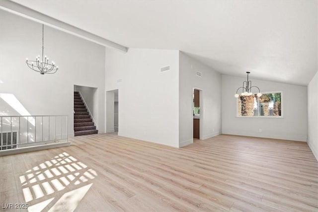 unfurnished living room with stairway, a notable chandelier, wood finished floors, and visible vents