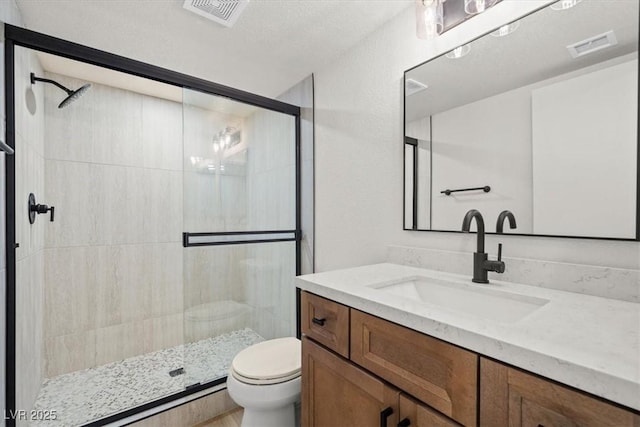 bathroom with visible vents, a shower stall, toilet, and vanity