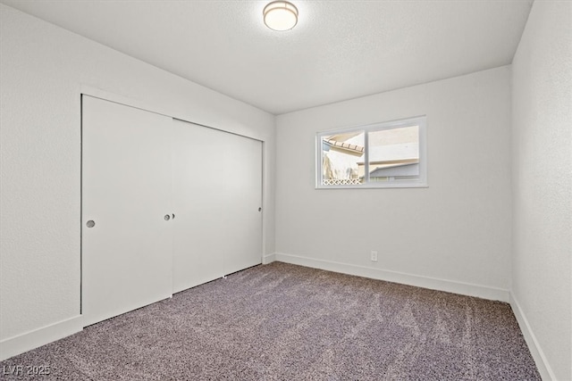 unfurnished bedroom with carpet flooring, baseboards, a closet, and a textured ceiling