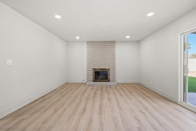 unfurnished living room with recessed lighting, baseboards, a fireplace, and light wood finished floors