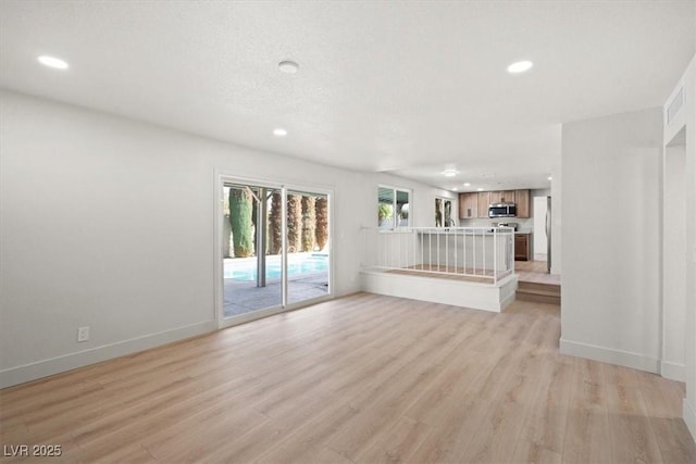 unfurnished living room featuring recessed lighting, light wood-type flooring, baseboards, and visible vents