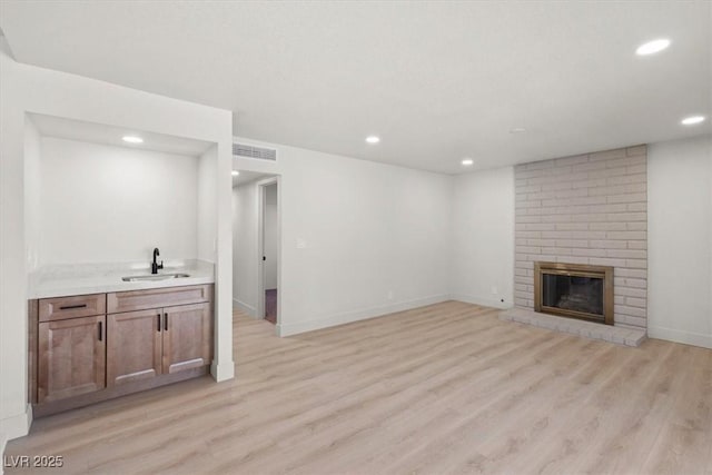 living area featuring visible vents, baseboards, recessed lighting, light wood-style flooring, and a fireplace