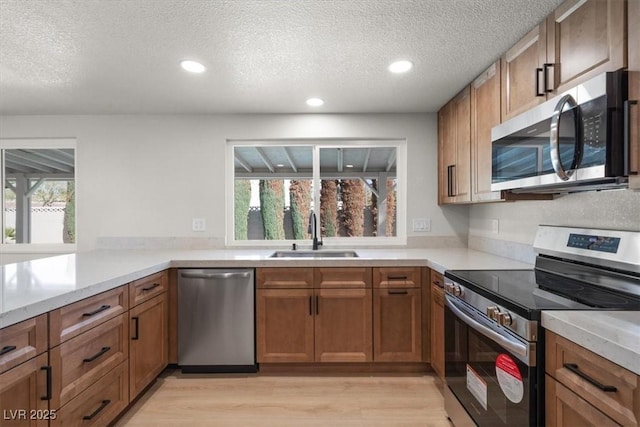 kitchen featuring brown cabinetry, a healthy amount of sunlight, stainless steel appliances, and a sink