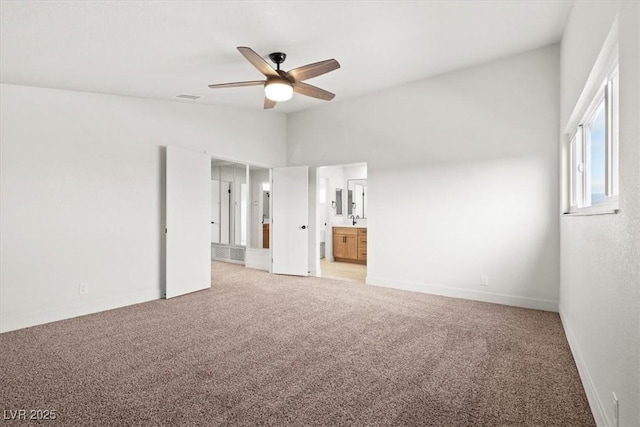 unfurnished bedroom with baseboards, visible vents, ensuite bath, vaulted ceiling, and light carpet