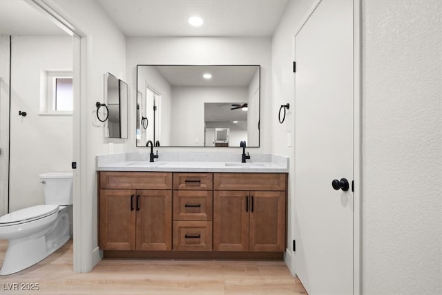 full bath featuring double vanity, wood finished floors, toilet, and a sink