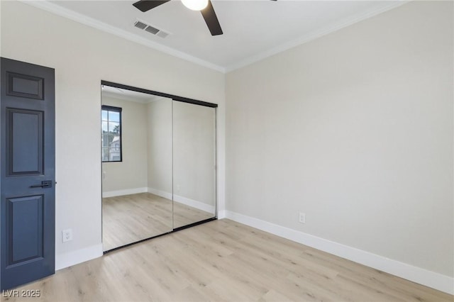 unfurnished bedroom with visible vents, ornamental molding, wood finished floors, a closet, and baseboards