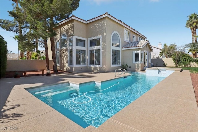 rear view of property featuring a patio, a fenced in pool, an in ground hot tub, a fenced backyard, and stucco siding