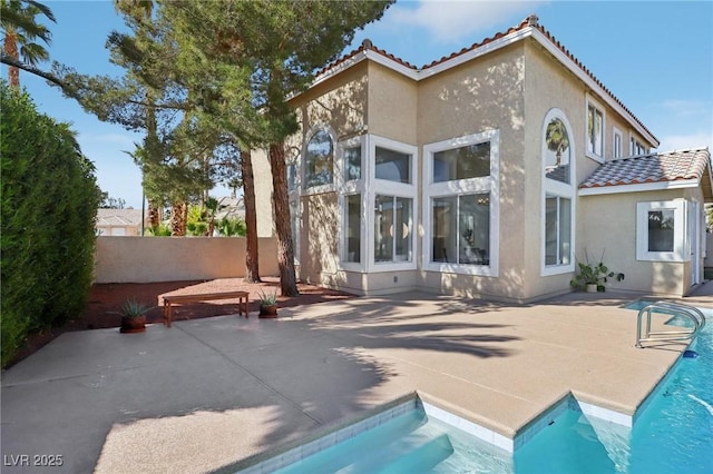 back of property with a patio, a tiled roof, a fenced in pool, and stucco siding